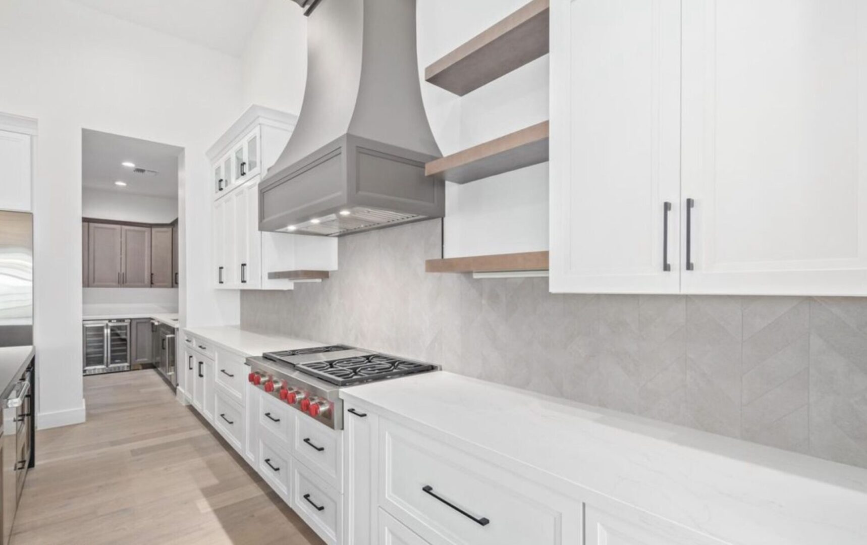 A kitchen with white cabinets and a silver hood.